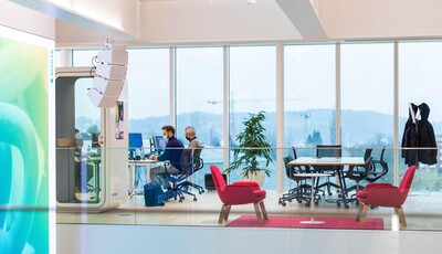 Innenansicht eines modernen Glasgebäudes mit intelligenter Verglasung, Menschen arbeiten an ihren Schreibtischen.